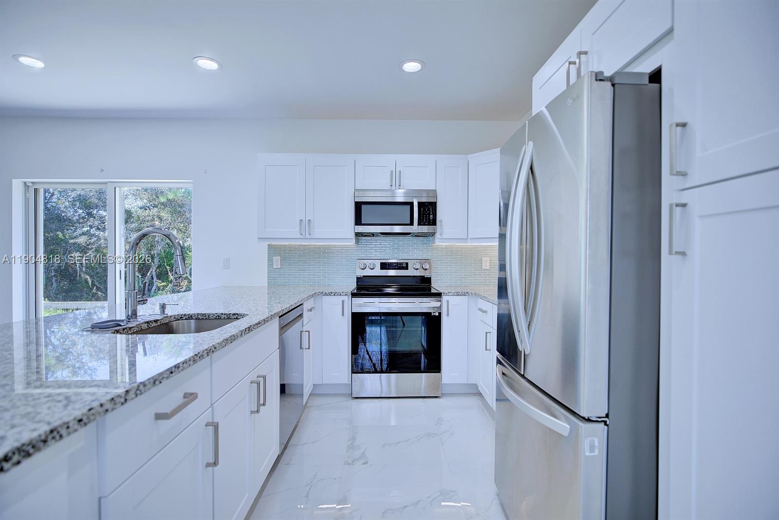 827 Renault Avenue Sebring, FL 33872 - Photo 13 of 27 a kitchen with granite countertop a refrigerator and a sink
