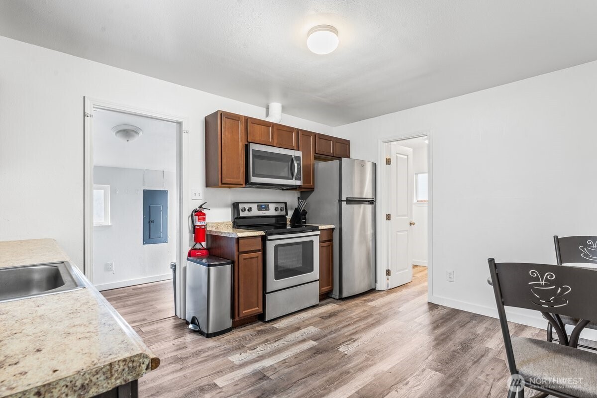 1916 Martin Luther King Junior Way Tacoma, WA 98405 - Photo 12 of 17 a kitchen with stainless steel appliances granite countertop a stove top oven a sink dishwasher a dining table and chairs with wooden floor