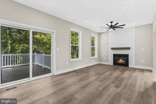 an empty room with windows fireplace and a ceiling fan