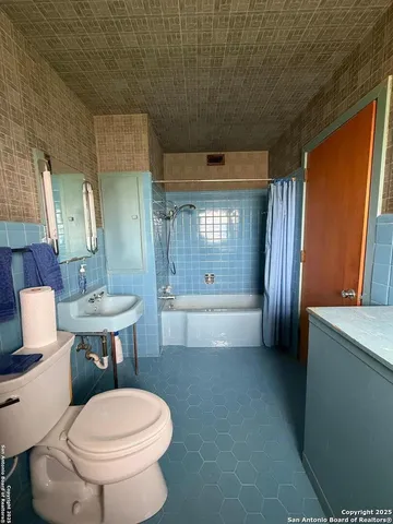 a bathroom with a sink a toilet a mirror and bathtub