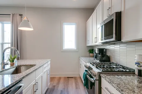 a living room with stainless steel appliances furniture a dining table and kitchen view