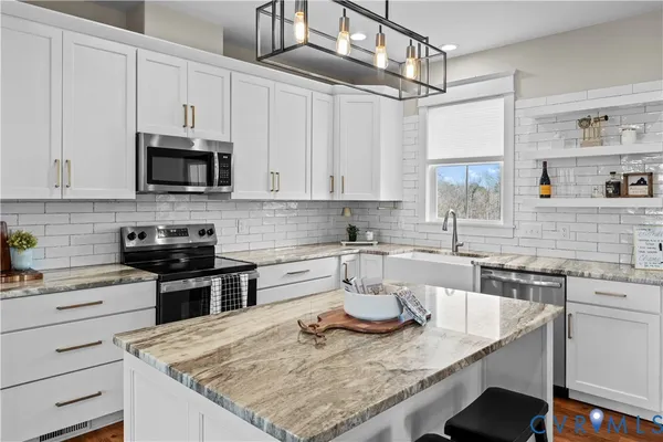a kitchen with kitchen island granite countertop stainless steel appliances a stove sink and microwave