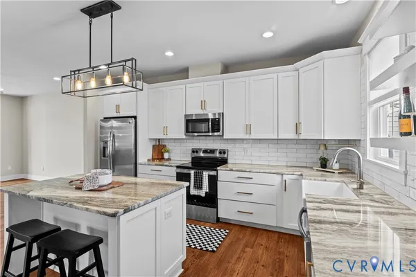 a kitchen with kitchen island granite countertop a sink a counter space stainless steel appliances and cabinets
