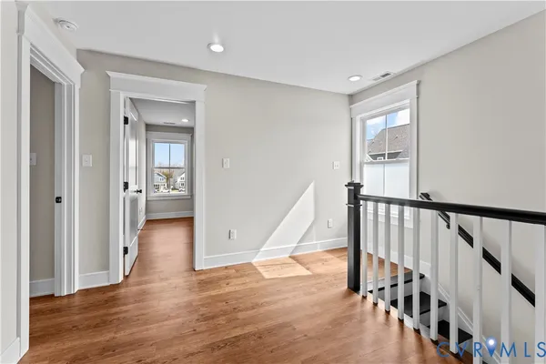 an empty room with wooden floor and windows
