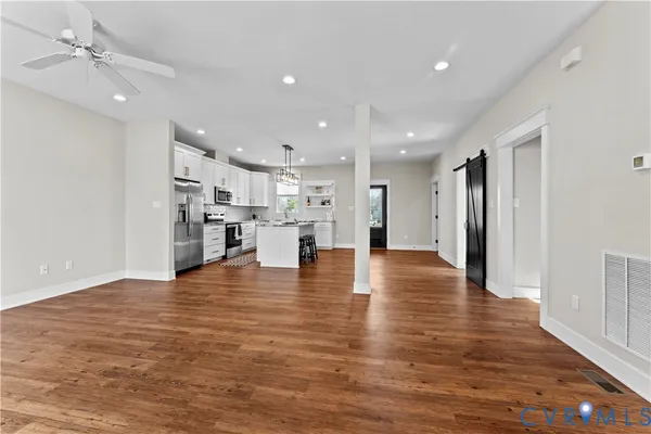 a view of kitchen with granite countertop wooden floor stainless steel appliances and a window