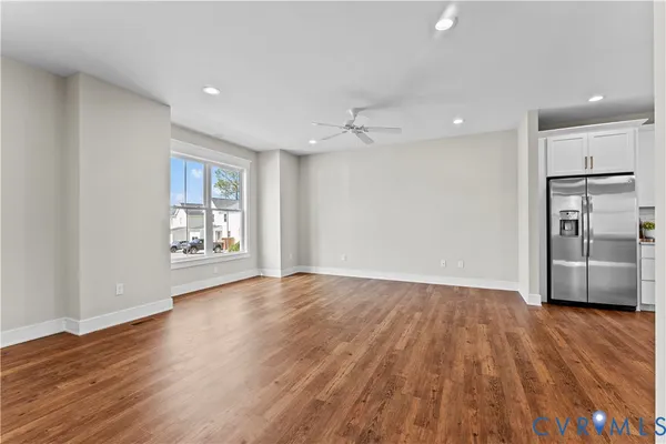 a view of an empty room with wooden floor and a kitchen