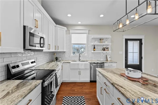 a kitchen with stainless steel appliances granite countertop a sink a stove a refrigerator cabinets and chairs