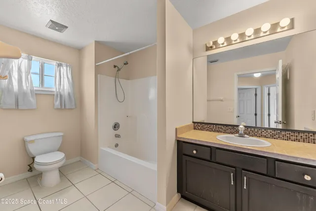 a bathroom with a granite countertop sink a toilet mirror and shower