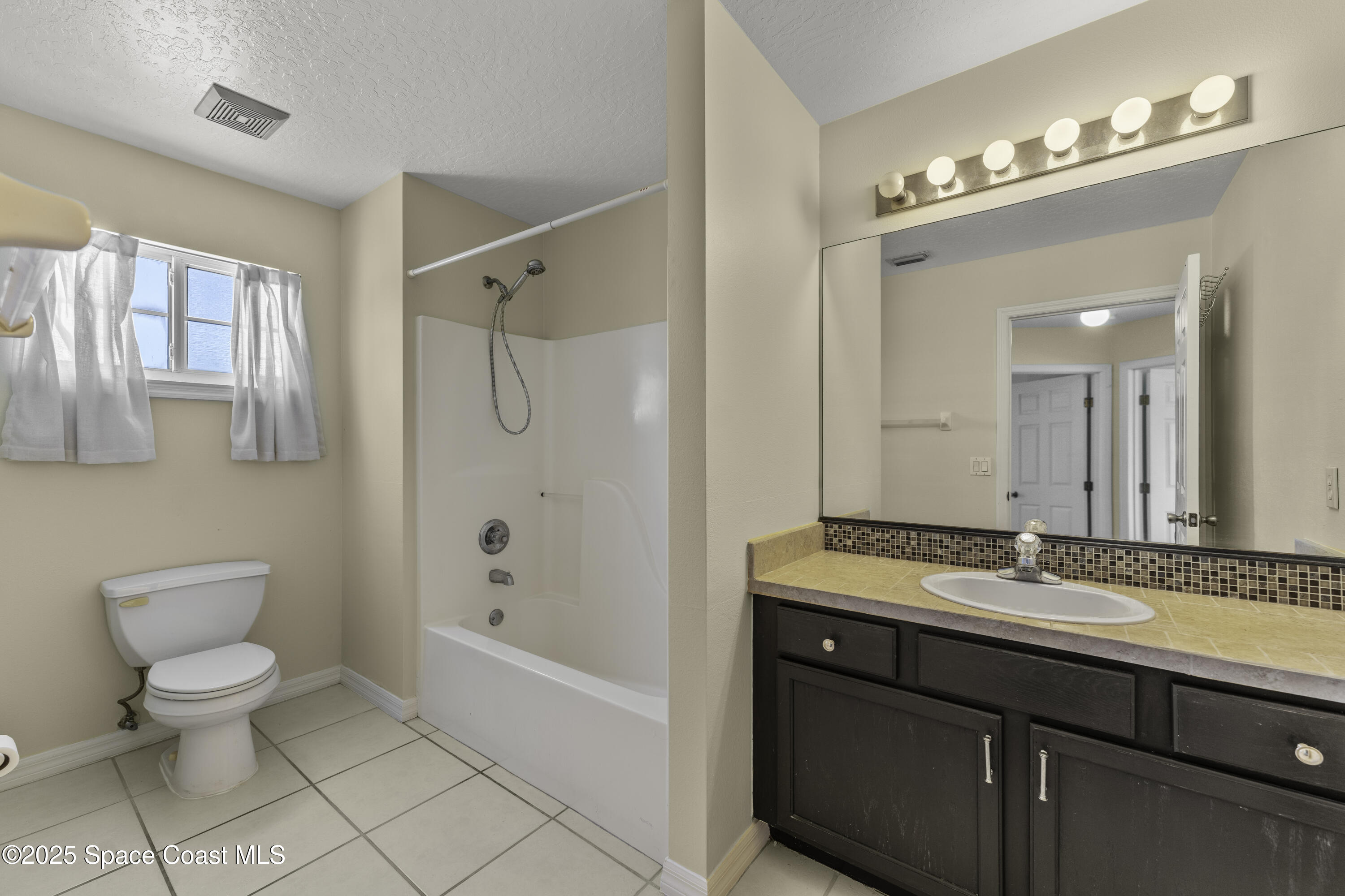 36 Sunset Street Satellite Beach, FL 32937 - Photo 29 of 45 a bathroom with a granite countertop sink a toilet mirror and shower