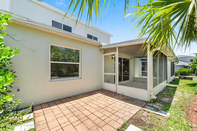 a view of a white house with a large window and potted plants