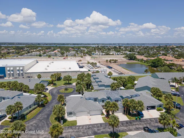 an aerial view of a city with lots of residential buildings and ocean view in back