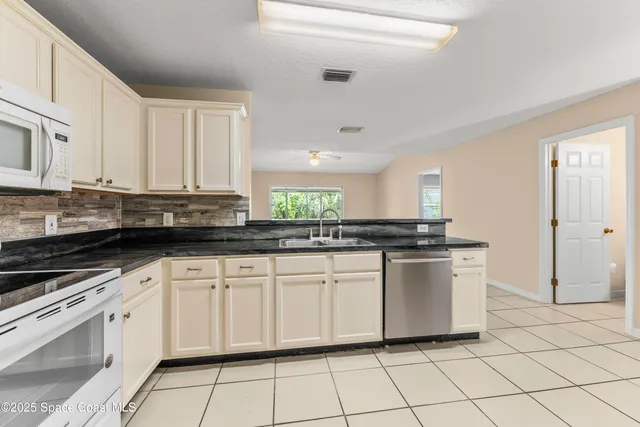 a kitchen with white cabinets a sink and white appliances