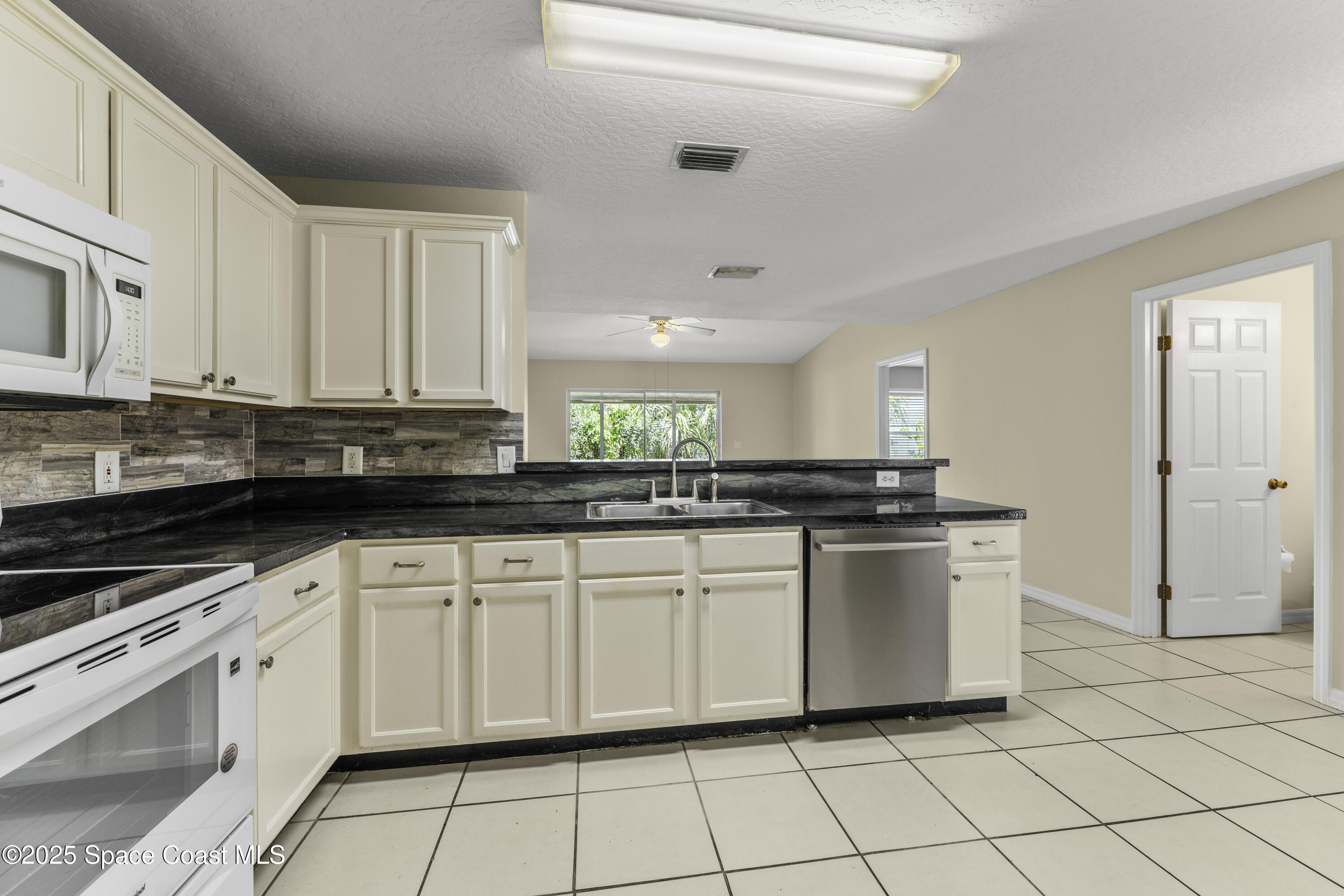 36 Sunset Street Satellite Beach, FL 32937 - Photo 6 of 45 a kitchen with white cabinets a sink and white appliances