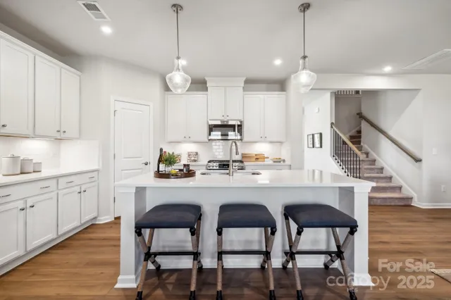 a kitchen with stainless steel appliances kitchen island granite countertop a dining table chairs and white cabinets