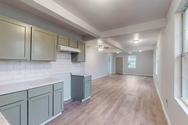 a view of a kitchen with wooden floor and cabinets