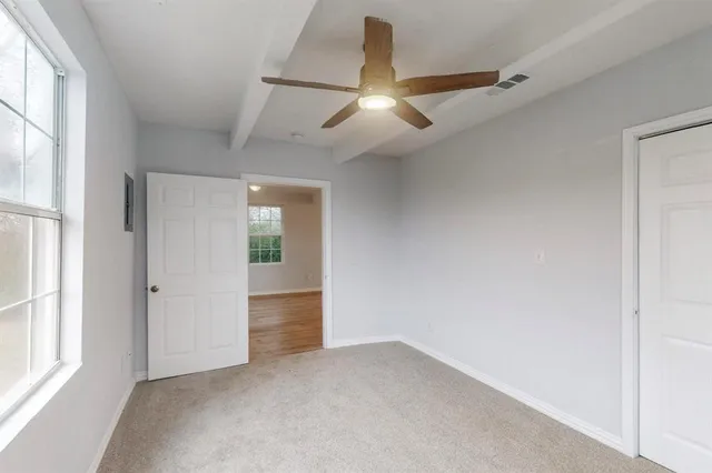 an empty room with chandelier fan and windows