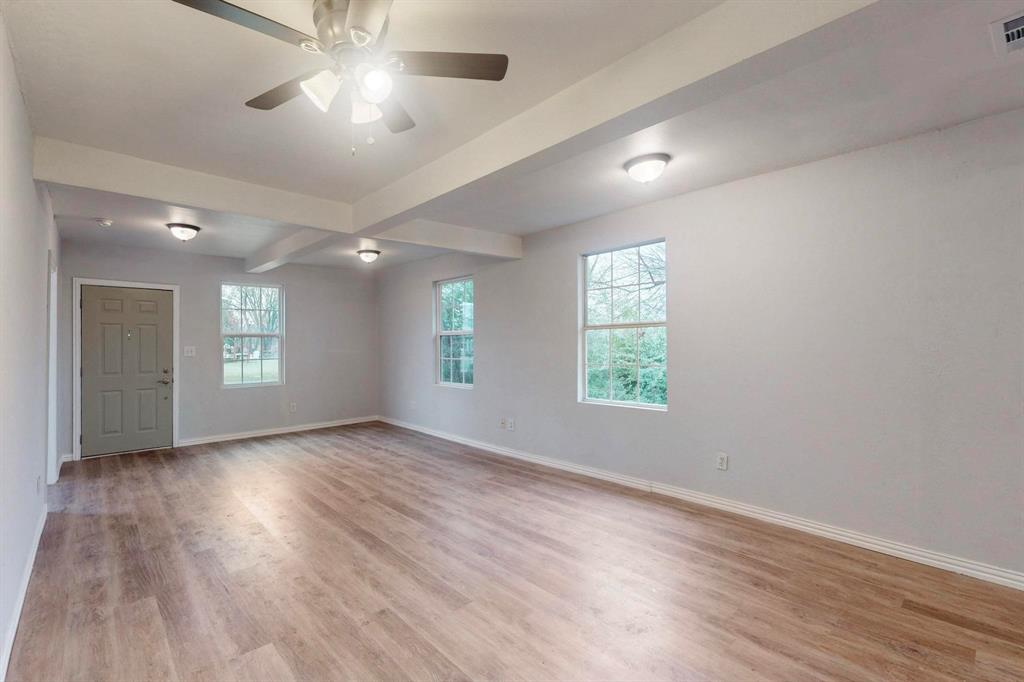 505 Oak Street Commerce, TX 75428 - Photo 2 of 28 an empty room with wooden floor and windows