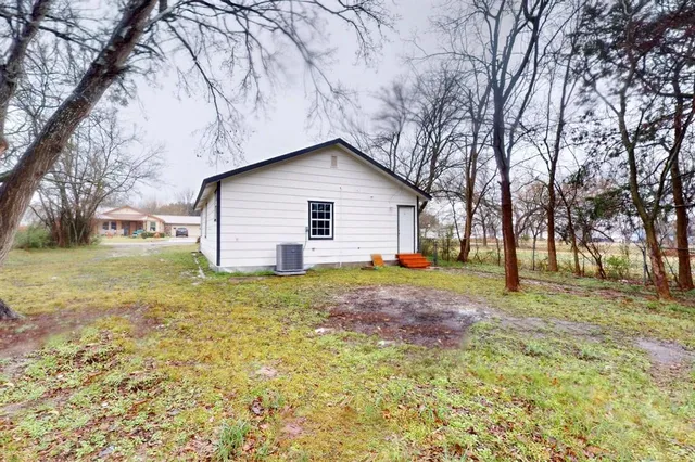 a backyard of a house with plants and large tree