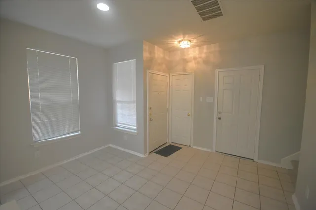 a view of an empty room with window and chandelier fan