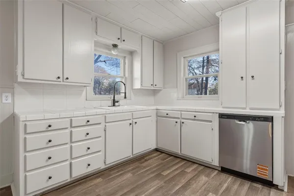 a kitchen with white cabinets and sink