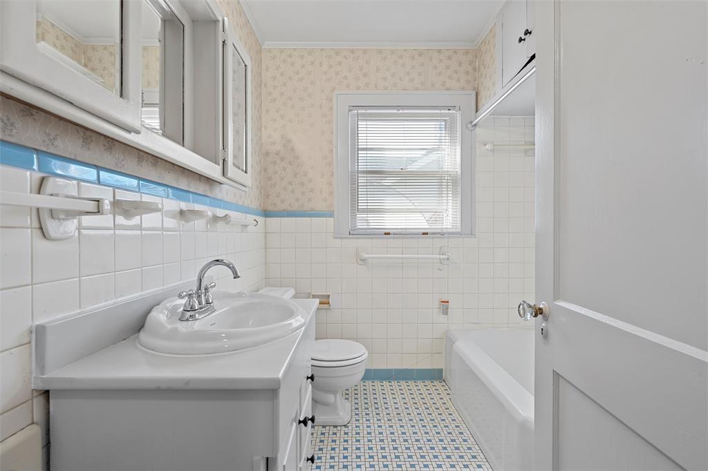 2912 Edmond Avenue Waco, TX 76707 - Photo 21 of 30 Bathroom with vanity, a wainscoted wall, wallpapered walls, shower combination, and tile walls