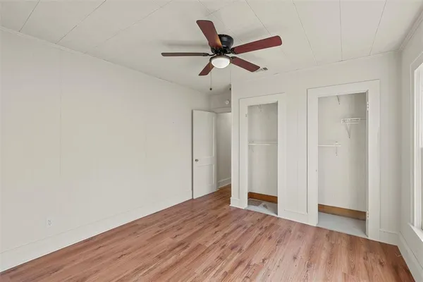 a view of empty room with wooden floor and ceiling fan