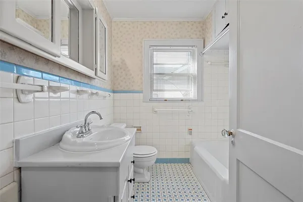 a bathroom with a sink a toilet a window and vanity