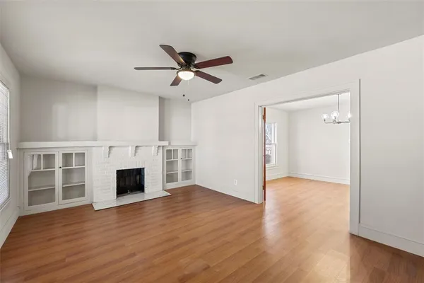 a view of an empty room with wooden floor fireplace and a window