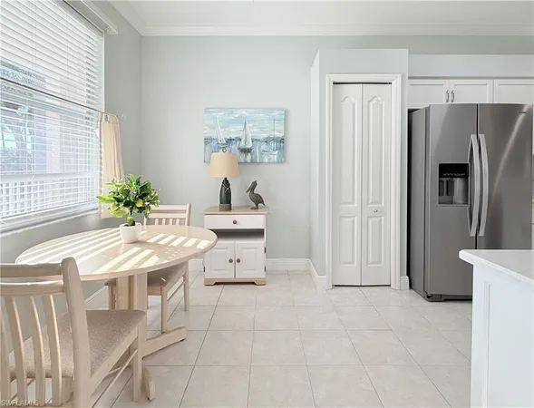 a living room with stainless steel appliances furniture a refrigerator and a window