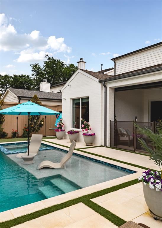 3963 Rochelle Drive Dallas, TX 75220 - Photo 38 of 40 Pool with integrated lounge area, surrounding stone patio with artificial turf accents, and white brick exterior
