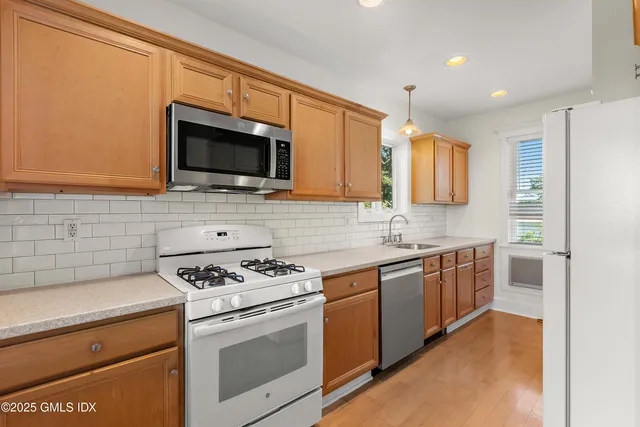 a kitchen with stainless steel appliances granite countertop a stove top oven a sink and a microwave