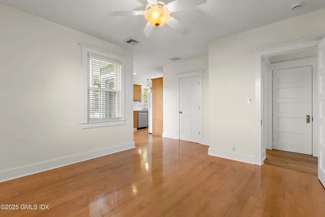 an empty room with wooden floor and windows