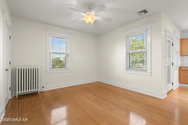 a view of empty room with wooden floor and fan
