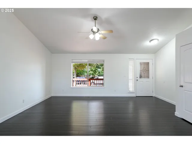 a view of an empty room with window and wooden floor