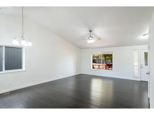 a view of an empty room with wooden floor and chandelier