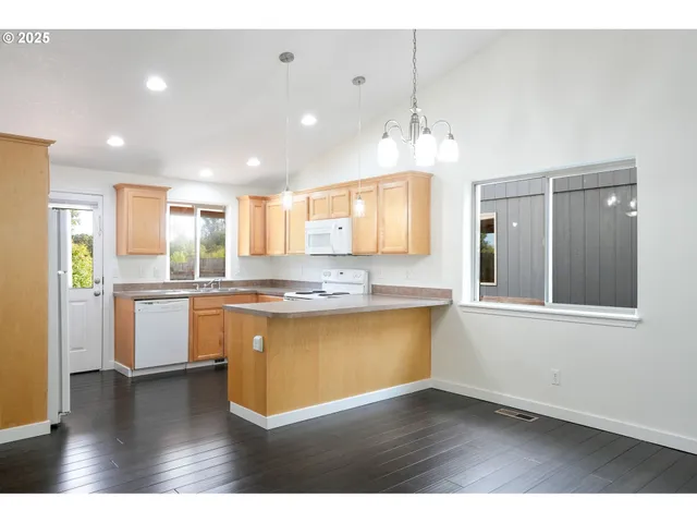 a large kitchen with kitchen island a sink dishwasher a stove and a dining table with wooden floor