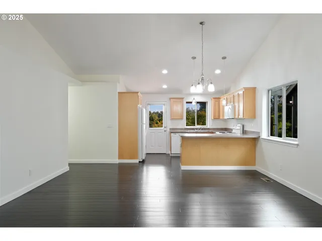 a view of a kitchen with kitchen island wooden floor appliances and a window