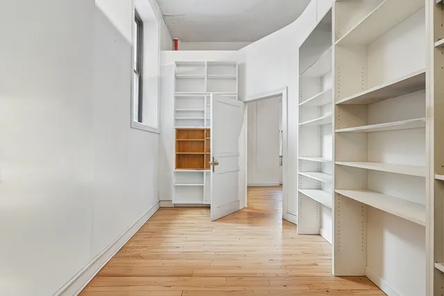 a view of walk in closet with wooden floor and fence