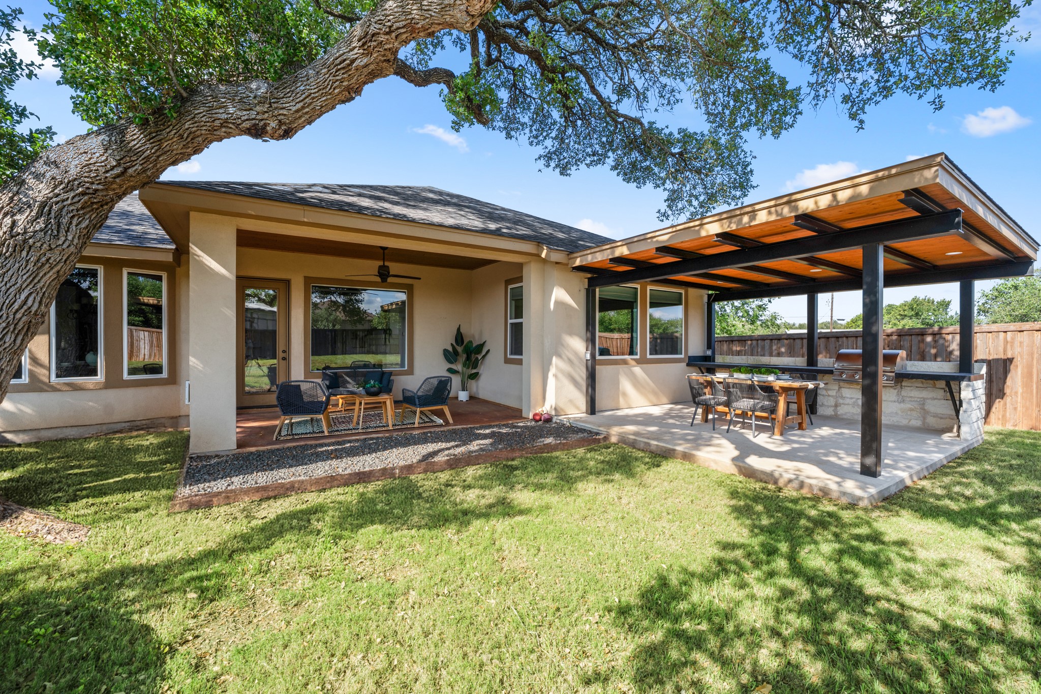 128 Hiram Cook Blanco, TX 78606 - Photo 31 of 40 Expansive backyard featuring a covered patio, separate outdoor kitchen area with stone base and wood-paneled ceiling, manicured lawn, and mature tree