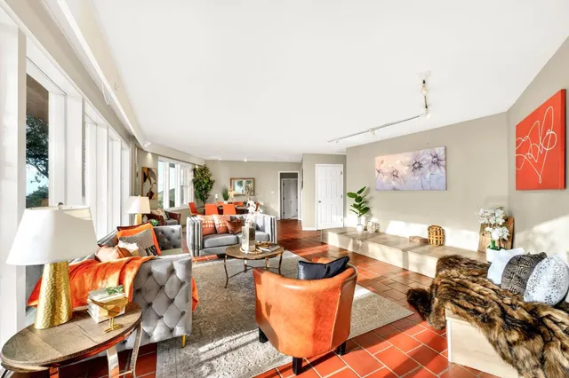 a living room with furniture potted plant wooden floor and a large window