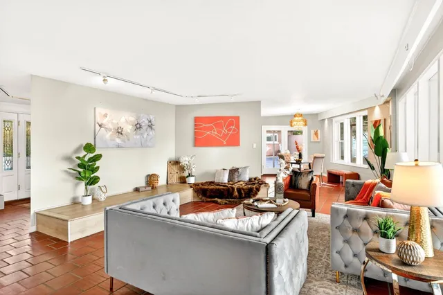a view of a dining room with furniture a chandelier and large windows