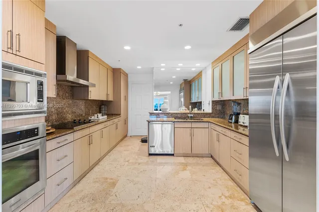 a large kitchen with stainless steel appliances granite countertop a stove a sink and a refrigerator