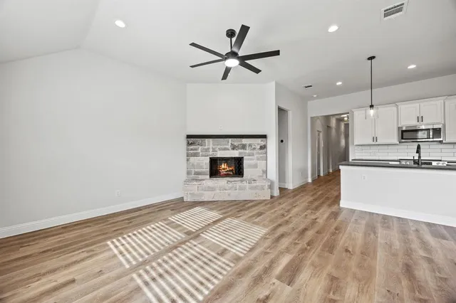 a kitchen with stainless steel appliances granite countertop a sink and a stove top oven with wooden floor