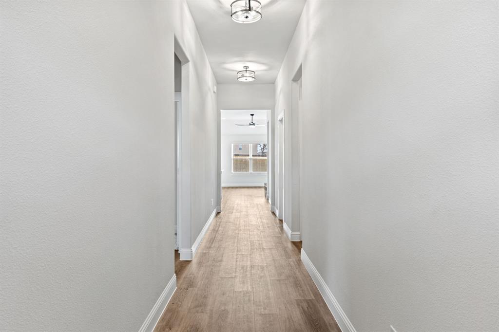 102 Maverick Trail Valley View, TX 76272 - Photo 25 of 32 a view of a hallway with wooden floor and a bathroom