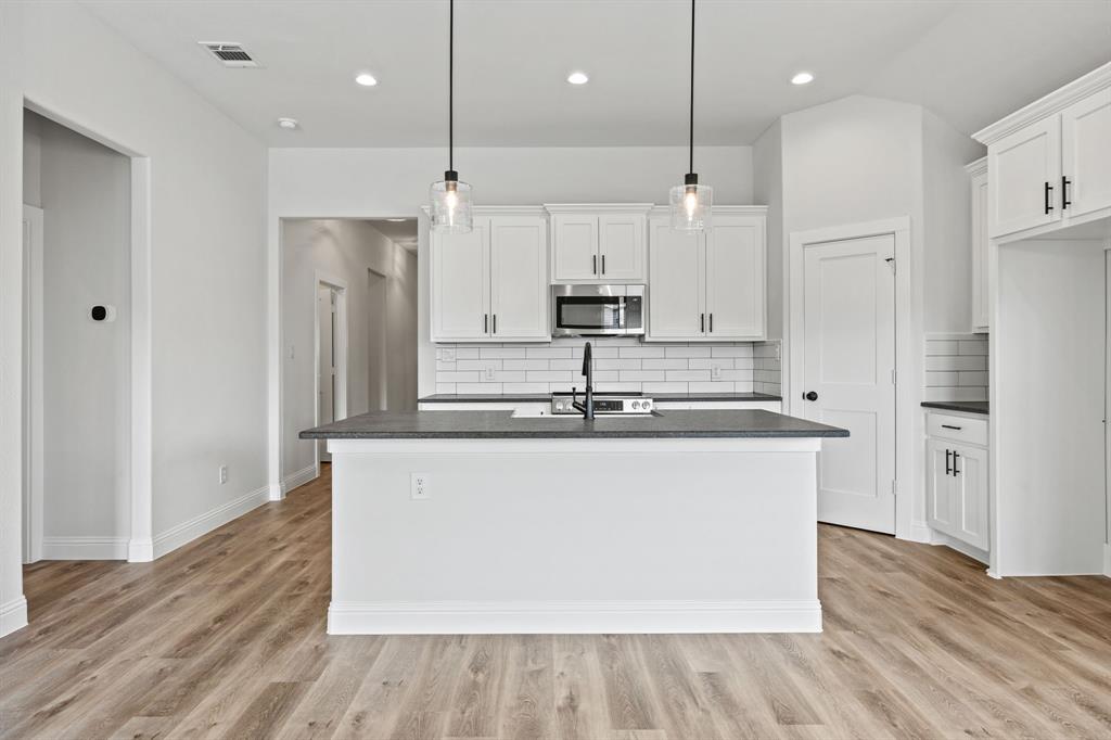102 Maverick Trail Valley View, TX 76272 - Photo 7 of 32 a large kitchen with stainless steel appliances a large counter top a refrigerator a stove and a sink