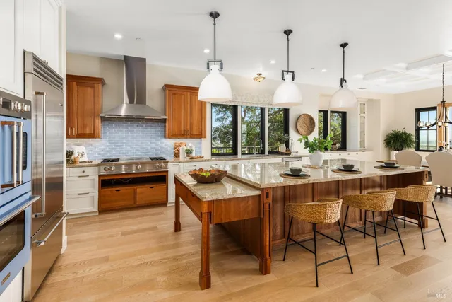 a kitchen with stainless steel appliances kitchen island granite countertop a stove a sink a refrigerator and a wooden cabinets