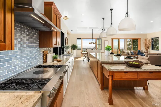 a kitchen with stainless steel appliances a stove a sink dishwasher a dining table and chairs with wooden floor