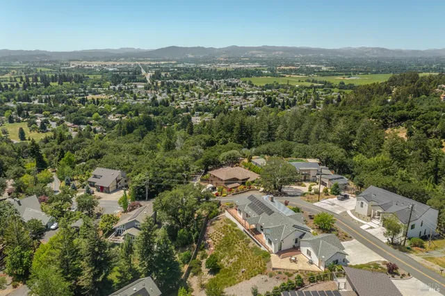 an aerial view of residential house with parking and trees