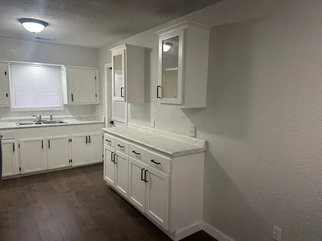 a kitchen with granite countertop white cabinets and white appliances