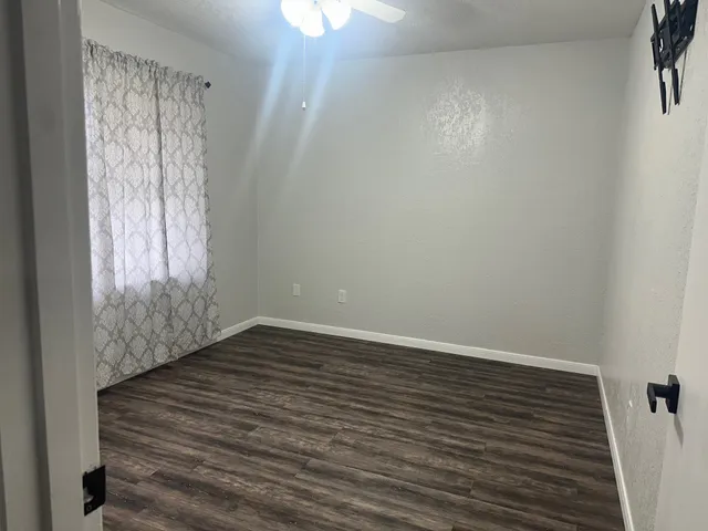 a view of an empty room with wooden floor and a window